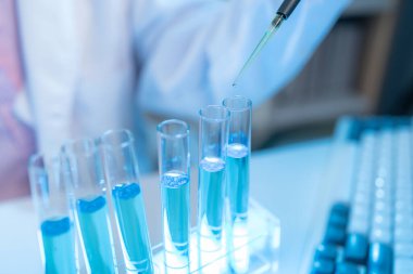 Bilimsel ekipman ve test tüpleriyle çevrili bir laboratuvarda kimya araştırmacısı, yenilikleri, bilimsel gelişimi ve modern tıbbi araştırma ortamını temsil ediyor..