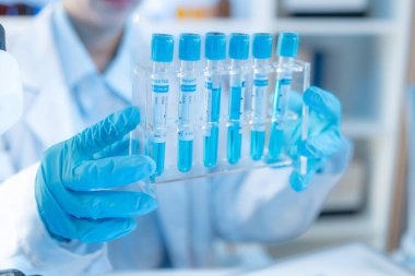 Bilimsel ekipman ve test tüpleriyle çevrili bir laboratuvarda kimya araştırmacısı, yenilikleri, bilimsel gelişimi ve modern tıbbi araştırma ortamını temsil ediyor..