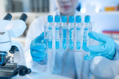 Bilimsel ekipman ve test tüpleriyle çevrili bir laboratuvarda kimya araştırmacısı, yenilikleri, bilimsel gelişimi ve modern tıbbi araştırma ortamını temsil ediyor..