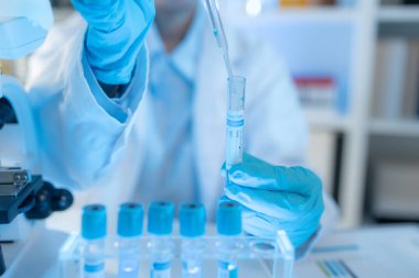 Bilimsel ekipman ve test tüpleriyle çevrili bir laboratuvarda kimya araştırmacısı, yenilikleri, bilimsel gelişimi ve modern tıbbi araştırma ortamını temsil ediyor..