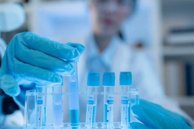 Bilimsel ekipman ve test tüpleriyle çevrili bir laboratuvarda kimya araştırmacısı, yenilikleri, bilimsel gelişimi ve modern tıbbi araştırma ortamını temsil ediyor..