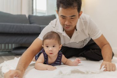Bir baba bebeğiyle kaliteli zaman geçirir. Yumuşak bir paspasın üzerinde nazik bakım ve eğlenceli anlarda oynayıp bağ kurar. Bebek karın zamanını ve emzik kullanımını destekliyor..
