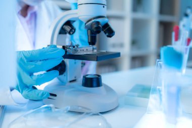 Bilimsel ekipman ve test tüpleriyle çevrili bir laboratuvarda kimya araştırmacısı, yenilikleri, bilimsel gelişimi ve modern tıbbi araştırma ortamını temsil ediyor..