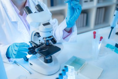 Bilimsel ekipman ve test tüpleriyle çevrili bir laboratuvarda kimya araştırmacısı, yenilikleri, bilimsel gelişimi ve modern tıbbi araştırma ortamını temsil ediyor..