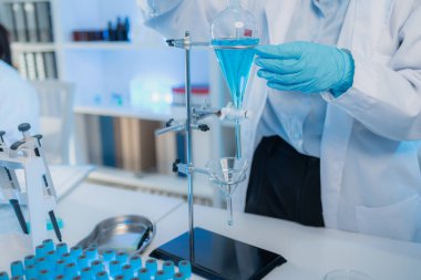 Bilimsel ekipman ve test tüpleriyle çevrili bir laboratuvarda kimya araştırmacısı, yenilikleri, bilimsel gelişimi ve modern tıbbi araştırma ortamını temsil ediyor..