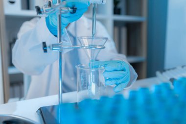 Bilimsel ekipman ve test tüpleriyle çevrili bir laboratuvarda kimya araştırmacısı, yenilikleri, bilimsel gelişimi ve modern tıbbi araştırma ortamını temsil ediyor..