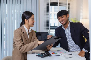 İş arkadaşları ortak bir tartışma içindeler, finansal tabloları ve raporları analiz ediyorlar. Fikir alışverişinde bulunurlar, stratejileri gözden geçirirler ve gelecekteki hedefleri planlarlar..