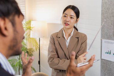 İş arkadaşları aktif olarak ortak bir toplantıda, çizelgeleri gözden geçiriyorlar, verilere işaret ediyorlar ve fikir alışverişinde bulunuyorlar. Takım çalışmaları strateji planlaması, analiz ve işbirliğini yansıtır..