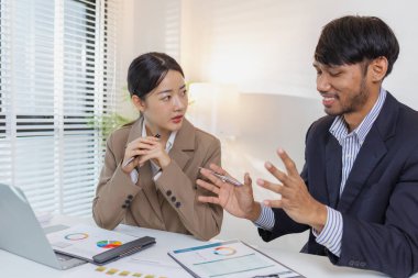 İki iş adamı, modern bir ofiste mali tablolar ve raporları tartışıyor. Birlikte çalışırlar, fikirleri paylaşırlar ve birlikte verileri analiz ederler, takım çalışmasını ve stratejisini vurgularlar..