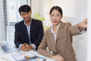 Ciddi bir ofis tartışmasına katılan bir grup profesyonel, mali raporları analiz ediyor ve sorunları çözmek ve etkili kurumsal kararlar almak için fikir alışverişinde bulunuyor..