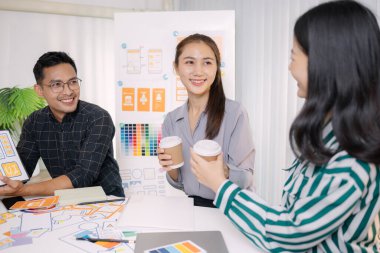 UX / UI tasarımcıları son tasarım projelerini takıma sunar, uygulama arayüzü ekranlarını gösterir ve profesyonel yaratıcı ofis ortamında kullanıcı deneyimi stratejilerini açıklar.