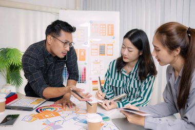 UX / UI tasarımcıları son tasarım projelerini takıma sunar, uygulama arayüzü ekranlarını gösterir ve profesyonel yaratıcı ofis ortamında kullanıcı deneyimi stratejilerini açıklar.