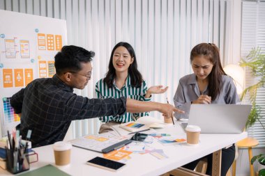 UX / UI tasarımcıları son tasarım projelerini takıma sunar, uygulama arayüzü ekranlarını gösterir ve profesyonel yaratıcı ofis ortamında kullanıcı deneyimi stratejilerini açıklar.