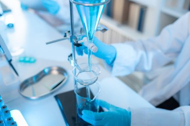 Bilimsel ekipman ve test tüpleriyle çevrili bir laboratuvarda kimya araştırmacısı, yenilikleri, bilimsel gelişimi ve modern tıbbi araştırma ortamını temsil ediyor..