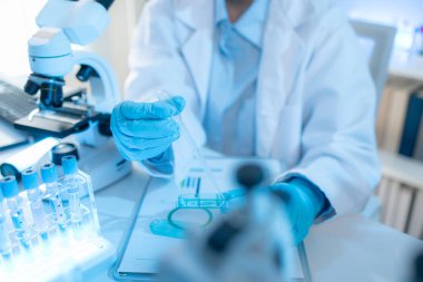 Bilimsel ekipman ve test tüpleriyle çevrili bir laboratuvarda kimya araştırmacısı, yenilikleri, bilimsel gelişimi ve modern tıbbi araştırma ortamını temsil ediyor..