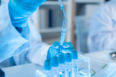 Bilimsel ekipman ve test tüpleriyle çevrili bir laboratuvarda kimya araştırmacısı, yenilikleri, bilimsel gelişimi ve modern tıbbi araştırma ortamını temsil ediyor..