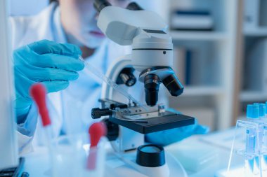 Bilimsel ekipman ve test tüpleriyle çevrili bir laboratuvarda kimya araştırmacısı, yenilikleri, bilimsel gelişimi ve modern tıbbi araştırma ortamını temsil ediyor..