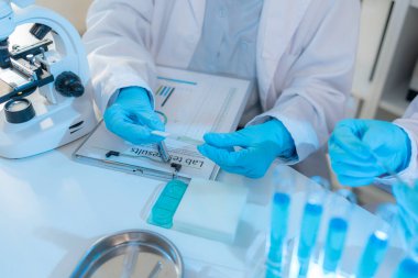 Bilimsel ekipmanlar, bilgisayarlar ve cam eşyalar ile çevrili modern bir laboratuvarda birlikte çalışan beyaz önlüklü iki kimyager, bilimsel araştırmalarda takım çalışmasını temsil ediyor..