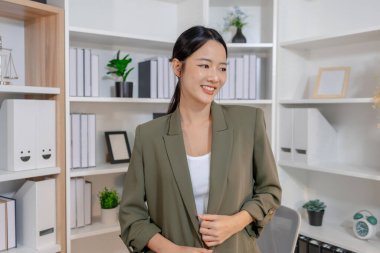 Bir ofis ortamında bağımsız çalışan, planlama ve günlük sorumluluklara odaklanan, kararlılık, profesyonellik ve dengeli bir çalışma tarzı gösteren iş kadını.