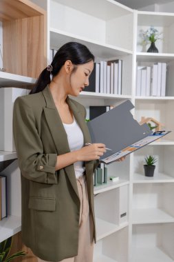 Bir ofis ortamında bağımsız çalışan, planlama ve günlük sorumluluklara odaklanan, kararlılık, profesyonellik ve dengeli bir çalışma tarzı gösteren iş kadını.