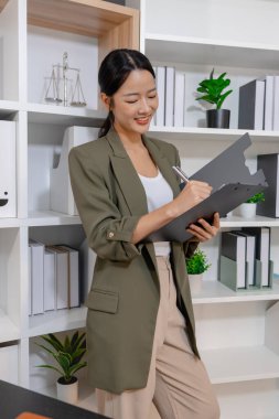 Bir ofis ortamında bağımsız çalışan, planlama ve günlük sorumluluklara odaklanan, kararlılık, profesyonellik ve dengeli bir çalışma tarzı gösteren iş kadını.