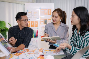 UX / UI tasarımcıları son tasarım projelerini takıma sunar, uygulama arayüzü ekranlarını gösterir ve profesyonel yaratıcı ofis ortamında kullanıcı deneyimi stratejilerini açıklar.