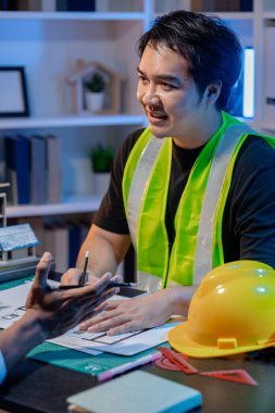 Bir mimari projenin koordinatlarını, tasarım kavramlarını ve modern inşaat gelişiminde verimlilik ve yaratıcılığı sağlamak için teknik planları gözden geçiren bir mimar ve mühendis ekibi..