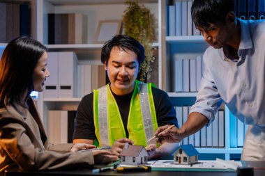 Bir mimari projenin koordinatlarını, tasarım kavramlarını ve modern inşaat gelişiminde verimlilik ve yaratıcılığı sağlamak için teknik planları gözden geçiren bir mimar ve mühendis ekibi..