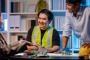 Bir mimari projenin koordinatlarını, tasarım kavramlarını ve modern inşaat gelişiminde verimlilik ve yaratıcılığı sağlamak için teknik planları gözden geçiren bir mimar ve mühendis ekibi..