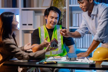 Bir mimari projenin koordinatlarını, tasarım kavramlarını ve modern inşaat gelişiminde verimlilik ve yaratıcılığı sağlamak için teknik planları gözden geçiren bir mimar ve mühendis ekibi..