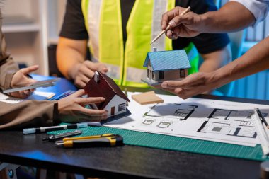 Bir mimari projenin koordinatlarını, tasarım kavramlarını ve modern inşaat gelişiminde verimlilik ve yaratıcılığı sağlamak için teknik planları gözden geçiren bir mimar ve mühendis ekibi..