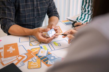 UX / UI tasarımcılarından oluşan bir grup, modern bir tasarım ofisinde yeni mobil uygulama arayüzü için renk paletleri ve konseptleri tartışarak yaratıcı fikirler üzerinde birlikte beyin fırtınası yapıyorlar..