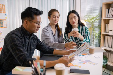 UX / UI tasarımcıları son tasarım projelerini takıma sunar, uygulama arayüzü ekranlarını gösterir ve profesyonel yaratıcı ofis ortamında kullanıcı deneyimi stratejilerini açıklar.