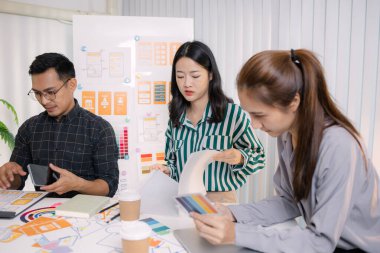 UX / UI tasarımcıları son tasarım projelerini takıma sunar, uygulama arayüzü ekranlarını gösterir ve profesyonel yaratıcı ofis ortamında kullanıcı deneyimi stratejilerini açıklar.