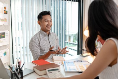Modern bir ofiste veri ve pazarlama raporlarını tartışan bir grup çok kültürlü meslektaşım. Ekip performans çizelgelerini analiz etmeye ve iş büyümesi için planlama stratejilerine odaklanıyor.