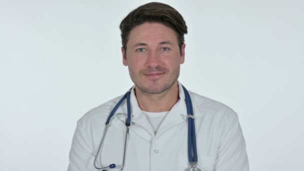 Médico masculino sonriendo a la cámara, fondo blanco — Vídeos de Stock