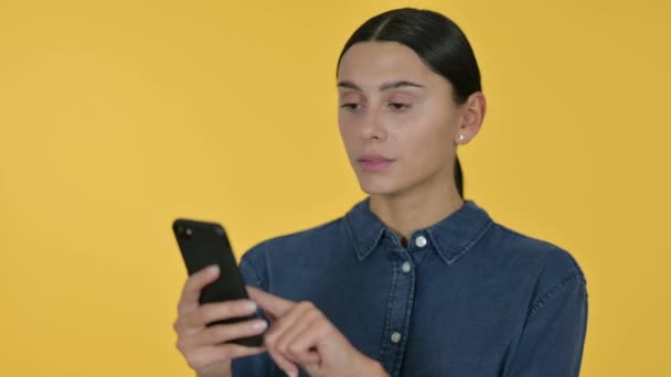 Jovem mulher latina usando Smartphone, fundo amarelo — Vídeo de Stock