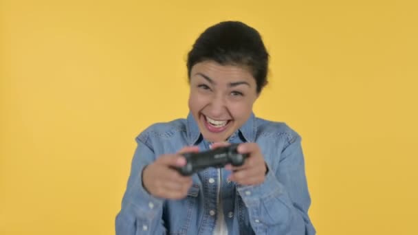 年轻的印度女人玩电子游戏，黄色背景 — 图库视频影像