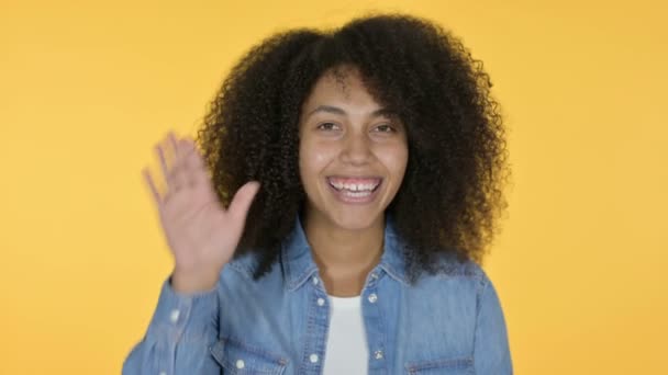 Ung afrikansk kvinna vinka, gul bakgrund — Stockvideo