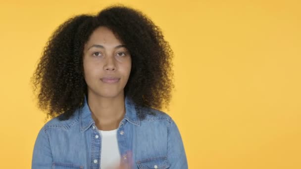 Молода африканка вказує на продукт, жовтий фон — стокове відео