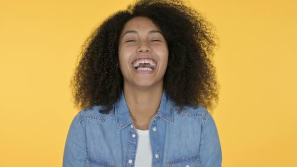 Счастливая молодая африканская женщина смеется, желтый фон — стоковое видео