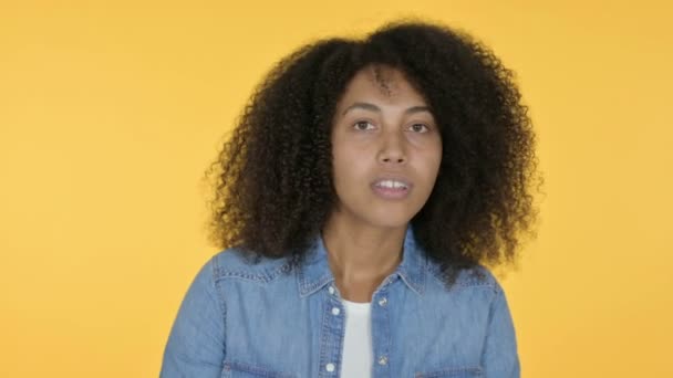 Jonge Afrikaanse vrouw op zoek rond te kijken, gele achtergrond — Stockvideo
