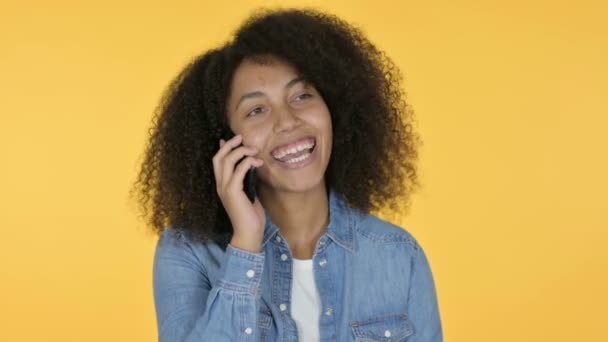 Joven mujer africana hablando en Smartphone, fondo amarillo — Vídeo de stock