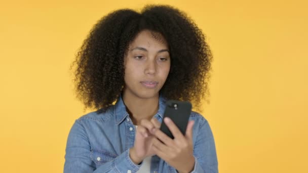 Молодая африканская женщина с помощью смартфона, желтый фон — стоковое видео