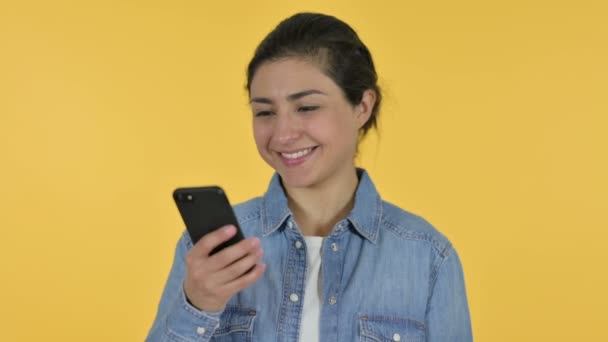 Молодая индийская женщина говорит на смартфоне, желтый фон — стоковое видео