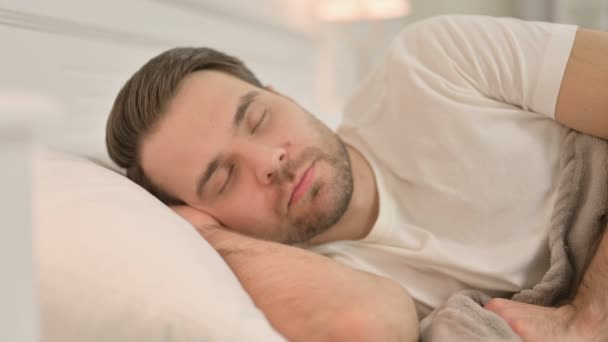 Porträt eines friedlichen jungen Mannes, der im Bett schläft — Stockvideo