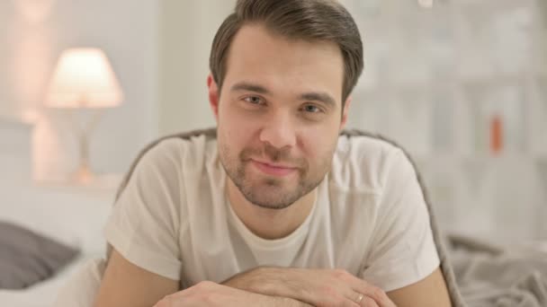 Close-up jonge man glimlachen bij camera, in bed — Stockvideo