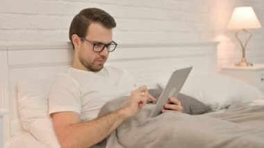 Yatakta Tablet 'te Kutlanan Heyecanlı Genç Adam 