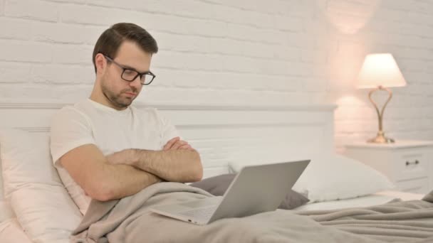 Schläfriger junger Mann mit Laptop schläft im Bett — Stockvideo