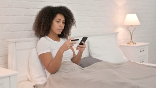 Успіх онлайн платежів на смартфоні африканської жінки в ліжку — стокове відео